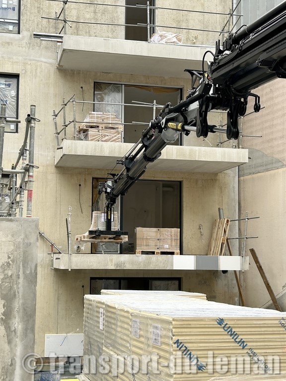 Levage d'une palette de carrelage avec grue palfinger et fourche en bout de jib sur un balcon