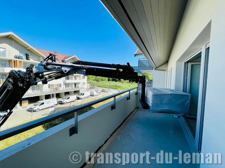 Levage d'une palette de carrelage avec fourche à palette sur bras de grue gris et noir photo depuis le balcon