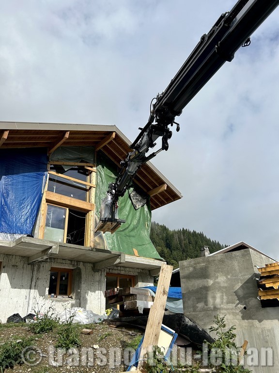 Levage d'un poêle à granule avec camion grue sur un balcon au premier étage. 